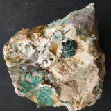 Fig. 18. Agregado esférico formado por el crecimiento divergente de cristales de tirolita creciendo sobre cristales de dolomita. En una matriz de dolomía se observan relictos de calcopirita en la parte izquierda de la matriz. Tamaño del agregado de tirolita 8 mm. Mina Los Picayos. Niserias. Peñamellera Alta. Asturias. Colección y foto Manuel Echevarría. (Autor: Echevarria)