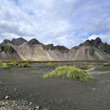 La playa de &rsquo;arena negra&rsquo; de Stokksnes está situada en el pueblo pesquero de Höfn, en Hornafjörður, región de Austurland, al sureste de Islandia. Es una extensa playa de dunas de varios kilómetros a los pies del glaciar Vatnajökull.
Cerca de la playa, está Vestrahorn con 454 metros de altura. Esta cadena montañosa se extiende entre los montes Húsadalstindur, en el oeste, y Brunnhorn, en el este. Su edad se estima entre 8 y 11 millones de años, cuando formó parte de un gran volcán central en la placa euroasiática. Sus laderas están formadas principalmente por gabro, una roca ígnea intrusiva de grano grueso y colores oscuros, compuesta por plagioclasa y piroxeno, que contiene muy poco cuarzo. Los gabros se han enfriado lentamente y sus cristales se han desarrollado más que en los basaltos, que son de enfriamiento más rápido. (Autor: Antonio P. López)