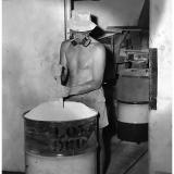 Processing El Sherana Uranium ore at moline

Shown is a photo of a worker ‘settling’ the Uranium ore concentrate into an appropriate steel container in a well-ventilated area. United Uranium N.L., Moline, Northern Territory, 1963. (Photo courtesy of J. Taylor)

The light colour of the product shown in the photo is indicative of Ammonium Uranyl Carbonate (AUC), commonly known as yellow-cake. An alternative compound supplied to the Nuclear Energy Industry is called AUD which is an abbreviation for Ammonium Diuranate, (NH4)2U2O7. AUD is much darker in colour than AUC with a greenish brown hue. For a detailed discussion on the solvent extraction of Uranium from Uranium ores see Ullmann&rsquo;s Encyclopedia of Industrial Chemistry, 40 Volume Set, 7th Edition, Section U, Uranium, Uranium Alloys, and Uranium Compounds; ISBN: 978-3-527-32943-4. (Author: silvia)