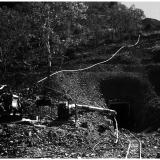 El Sherana Mine Photo showing Adit

An old adit set into a hill at El Sherana, note tracks leading into an adit (perhaps the 195 metre level) and the visible water pipes and machinery, El Sherana, NT late 1950’s. (Photo courtesy of R. Fisher) (Author: silvia)