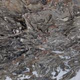 _Parece ser un gneiss muy replegado resultado del metamorfismo de alto grado de un esquisto biotítico. Por fundir antes que el resto de minerales que forman el esquisto, el cuarzo de segregación se acumula formando almohadillas. (Autor: Josele)