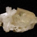 Calcite + stilbite. Nice yellowish rhombohedral calcite crystal to 15mm on the front edge, associated with small white stilbite crystals. Specimen is 37mm wide x 20mm high x 20mm deep. Self-collected 1992 from Sgurr an Duine, Minginish, Isle of Skye. ( Sgurr an Duine is the cliff/beach immediately north of Sgurr nam Boc.) (Author: Mike Wood)