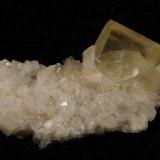 Calcite + chabazite. A not-so-good photo showing a nice yellowish transparent calcite rhomb to 15mm on edge, on a bed of small chabazite crystals. Specimen is 50mm x 25mm x 22mm. Self-collected 1999 from Moonen Bay, Duirinish, Isle of Skye. (Author: Mike Wood)