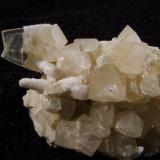 Calcite + stilbite. The only decent specimen showing the third habit of calcite at this locality. A ’butterfly’ twinned and flattened scalenohedral crystal measuring 25mm x 19mm is partially coated with micro stilbites, as is the more common elongated scalenohedral ’dog-tooth’ habit of crystal. The later more simple rhombohedral calcites appear to have been deposited after the earlier forms af calcite were covered with the micro stilbite crystals. Specimen measures 80mm wide (not all shown in the photo) x 45mm high x 40mm deep. Self-collected 1998 from Camas na h-Uamha, Duirinish, Isle of Skye. (Author: Mike Wood)