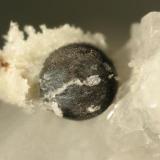 Compact spherical aggregate of graphite crystals partially dissolved from enclosing calcite matrix. (1-mm diameter) (Author: John Jaszczak)