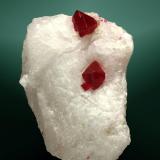 Espinela (espinela rubí)
Mogok, Sagaing (div.), Mandalay, Myanmar (Burma).
4,3 x 3,7 x 2,2 cm. (ejemplar) / 0,9 x 0,6 x 0,5 cm. (cristal pral.)
Dos cristales octaédrics maclados, rojos, transparentes, incluidos en matriz de marmol sacaroide blanco.
Ejemplar de 2001 (Autor: Carles Curto)