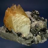 Calcite with Sphalerite on Calcite
Elmwood Mine, Middle Tennessee District, Carthage, Smith County, Tennessee, USA
160 x 140 x 117 mm
A lustrous, twinned crystal of golden Calcite measuring 107 x 83 x 36 mm is perched on a plate of limestone matrix covered with sparkling,
clear scalenahedrons of Calcite. Bright rich-red Sphalerite crystals to 14 mm generously cover the specimen (Author: GneissWare)