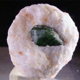 Diópsido sobre mármol
Koksha Valley, Khash & Kuran Wa Munjan Districts,  Badakhshan Province, Afganistán
5,5 x 5 x 5 cm.
El cristal mide 2,5 cm. Estos diópsidos de magnífico color y contraste sobre el mármol presentan unas caras bastante curvadas (debido posiblemente a un desarrollo más rápido de la parte central de las caras que da lugar a características formaciones tipo barril -recordamos las vanadinitas de Toussit-). Está biterminado, aunque la terminación más descubierta presenta algo de etching. Véanse las marcas perpendiculares al eje c que trataré de explicar a continuación (Autor: Antonio Alcaide)