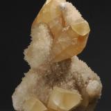 Calcite
Gallatin Canyon, Montana, USA
17 X 10 X 6 cm
This is a fine, classic Gallatin Canyon calcite specimen. It is nearly a floater, I can find only two 1-cm points of attachment from what must have been a large pocket with branching, lobular matrices in it, covered with tiny calcites. On top of those grew the large golden scalenohedrons. The largest calcite is 7.5 cm (3 inches) and is doubly terminated. All the large scalenohedrons are undamaged. The overall size of this grand specimen is 17 X 10 X 6 cm. The specimen was passed from Ronald L. Anderson of Littleton, CO to the Buckskin Booksellers of Ouray, CO. I purchased in from Robert Stouffer, also of Ouray, CO. (Author: John Nash)