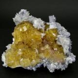 A group of cubic crystals of yellow honey color, very bright and transparent, skirted by bluish tabular crystals of Barite and covered by little scalenohedra of Calcite. 
Moscona Mine (Author: Joan Rosell)
