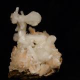 Stilbite + Heulandite
Sgurr nam Boc, Isle of Skye, Scotland, UK
8cm x 7cm x 8cm high
Pretty combination, very rarely seen at this locality, of pink heulandite crystals with white bowtie stilbite crystals. The stilbite at the top is 4cm long. This specimen was found in the remains of a large boulder which had been ’attended to’ by a joint Scottish Museum trip (by boat) a few weeks earlier !
Self-collected 1997 (Author: Mike Wood)