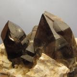 Smoky Quartz + Microcline
Isle of Arran, Scotland, UK
12cm x 7cm x 6cm high
Closer view of the two smoky quartz crystals on the specimen as above; the smaller one on the left is 35mm tall and slightly dinged on the termination. The larger one on the right is 57mm tall and undamaged. (Author: Mike Wood)