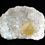Fluorite
Mahodari Quarry, Nasik, Maharashtra, India
6.5 x 9.0 cm.
A translucent, yellow sphere of fluorite resting on a concave bed of quartz crystals. (Author: crosstimber)