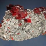 Realgar
Jiepaiyu Mine, Shimen, Changde Pref., Hunan Prov., China
4.5 x 6.4 cm.
Lustrous cherry-red realgar crystals on a silicified gray matrix with small tufts of acicular white picropharmacolite. (Author: crosstimber)