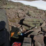 This was my bed for the night before, on a mat in a bivi bag in a rocky niche. I was planning on sleeping on a nice grassy spot around the corner but the wind got up and it was cold, so I moved here for shelter. It was more comfortable than it looks! (Author: Mike Wood)