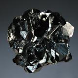 Hematite
N’Chwaning II Mine, Kuruman, N. Cape Province, South Africa
3.9 x 4.0 cm
Lustrous metallic black hematite crystals with a small colorless calcite rhomb. (Author: crosstimber)