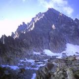 The South Face of the Aiguille du Moine, above the spot where I was bivouacing for the night. The cave where I found the crystals is high on the upper part of the South Face. The next morning I climbed up the mountain from the top of the snowfield, trending leftwards along ledges to reach a gully, which eventually led to the arete on the left. Then the climbing got even harder..
Photo scanned from slide. (Author: Mike Wood)