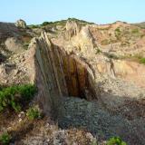 Caliza. Otras pequeñas canteras artesanales. De esta corta sale actualmente la piedra de mejor calidad: grande, lisa y uniforme. Las capas finas (1 – 2 cm) se usan para revestimientos verticales y las mas gruesas para solería. La mayor parte de la producción se vende tal cual sale, con contorno irregular, aunque por encargo las mejores losas se trabajan a cincel hasta dejarlas a medida. (Autor: Josele)