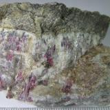 Pegmatita con turmalina
Animikie Red Ace Pegmatite, Condado Florence, Wisconsin, Estados Unidos
6 x 4’5 cm.
Zona de contacto entre la roca encajante (arriba, de grano fino) y la pegmatita intruida.  Ésta muestra cristales rosas de elbaíta (turmalina) junto al cuarzo de tono gris, y la mica lepidolita de color pardo a la derecha. (Autor: prcantos)