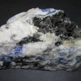 Sienita nefelínica con sodalita
Sørøya, Hasvik, Finnmark, Noruega
8 x 5 cm.
Además de las zonas claras (con nefelina y feldespato alcalino) y la sodalita azul, se distingue una placa oscura y brillante de biotita. (Autor: prcantos)